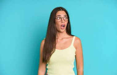 İspanyol güzel kadın şaşkın, mutlu, şaşkın ve şaşırmış hissediyor, ağzı açık bir şekilde yana bakıyor.