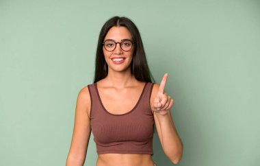 İspanyol güzel kadın gülümsüyor ve arkadaş canlısı görünüyor, bir numarayı gösteriyor ya da ilk eli önde, geri sayıyor.