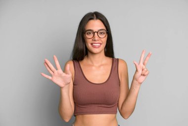 İspanyol güzel kadın gülümsüyor ve arkadaş canlısı görünüyor, 8 ya da 8 numarayı gösteriyor, elleri önde, geri sayıyor.