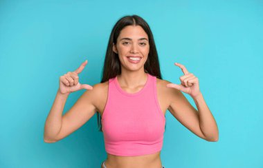 İspanyol asıllı güzel bir kadın iki eliyle kendi gülüşünü çiziyor, olumlu ve mutlu görünüyor, sağIık kavramı.