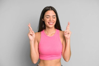 İspanyol güzel kadın gülümsüyor ve endişeyle iki parmağını çapraz yapıyor. Endişeli hissediyor, iyi şanslar diliyor ya da umut ediyor.