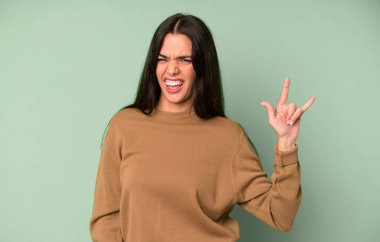 İspanyol güzel kadın kendini mutlu, eğlenceli, kendinden emin, pozitif ve asi hissediyor, elle rock veya heavy metal işareti yapıyor.