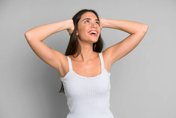 hispanic pretty woman smiling and feeling relaxed, satisfied and carefree, laughing positively and chilling