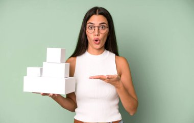 İspanyol güzel kadın şaşırmış ve şok olmuş görünüyor, çenesi düşmüş beyaz boş kutularla bir nesne tutuyor