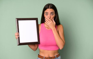 İspanyol asıllı güzel bir kadın elleri ile ağzını kapatıyor ve boş bir çerçeve kullanıyor.