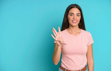 İspanyol güzel kadın gülümsüyor ve arkadaş canlısı görünüyor, dört numarayı gösteriyor. boşluk konseptini kopyala