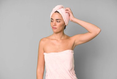 İspanyol güzel kadın mutlu bir şekilde gülümsüyor ve hayal kuruyor ya da şüphe ediyor. Bornoz ve güzellik konsepti