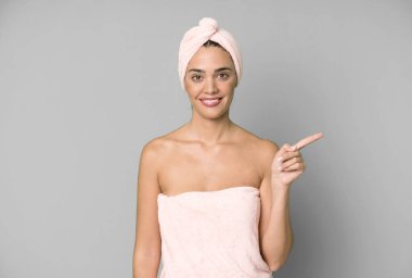 İspanyol güzel kadın neşeyle gülümsüyor, mutlu hissediyor ve bir tarafı işaret ediyor. Bornoz ve güzellik konsepti