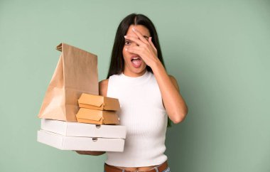 İspanyol güzel kadın şok olmuş, korkmuş ya da korkmuş görünüyor, yüzünü elleriyle kapatıyor. boş ambalaj kutularını kaldır