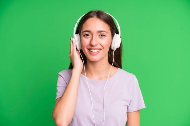 Genç ve güzel bir kadın kulaklıklarıyla müzik dinliyor.