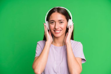 Genç ve güzel bir kadın kulaklıklarıyla müzik dinliyor.