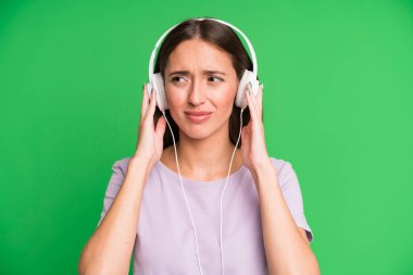 Genç ve güzel bir kadın kulaklıklarıyla müzik dinliyor.