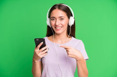 Genç ve güzel bir kadın kulaklıklarıyla müzik dinliyor.