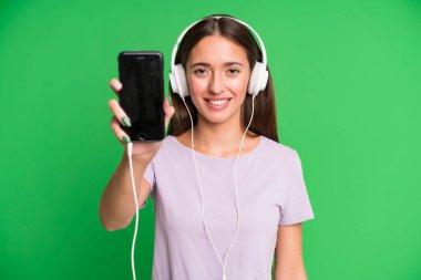 Genç ve güzel bir kadın kulaklıklarıyla müzik dinliyor.