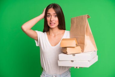 Genç, güzel bir kadın stresli, endişeli ya da korkmuş hissediyor. Elleri kafasında kağıt maketi olan. Fast food paketlerini alıp götürüyor.