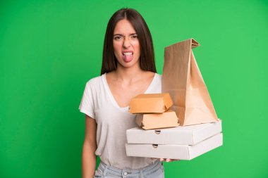 Genç ve güzel bir kadın, tiksinmiş ve rahatsız olmuş hissediyor. Dilini kağıt maketi ile çıkarıyor. Fast food ambalajlarını çıkarıyor.