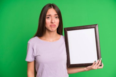 Genç, güzel bir kadın üzgün ve sızlanıyor. Mutsuz bir bakışla ve boş bir çerçeve ile ağlıyor.