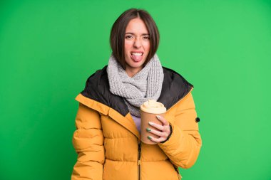 Genç, güzel bir kadın tiksinmiş ve rahatsız olmuş hissediyor. Dili dışarıda palto giyiyor ve elinde kahve tutuyor.