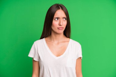 Hispanik güzel kadın üzgün, üzgün ya da kızgın hissediyor ve olumsuz bir tutumla yan yana bakıyor, anlaşmazlık içinde kaşlarını çatıyor