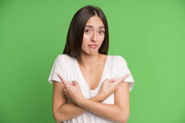 İspanyol güzel kadın şaşkın ve şaşkın görünüyor, güvensiz ve zıt yönlere şüpheyle işaret ediyor.