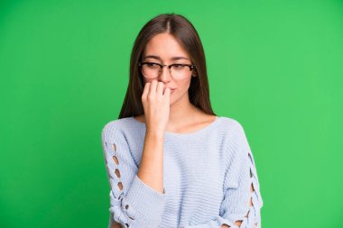 Hispanik güzel kadın ciddi, düşünceli ve endişeli, elleri çenesine bastırılmış şekilde yan bakıyor