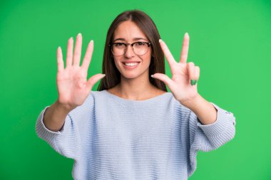 İspanyol güzel kadın gülümsüyor ve arkadaş canlısı görünüyor, 8 ya da 8 numarayı gösteriyor, elleri önde, geri sayıyor.