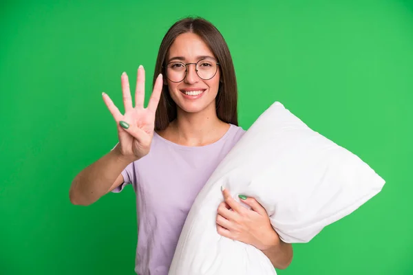 若い女性は笑顔で友好的に見える4番目を示しています パジャマと枕付きのナイトウェア — ストック写真