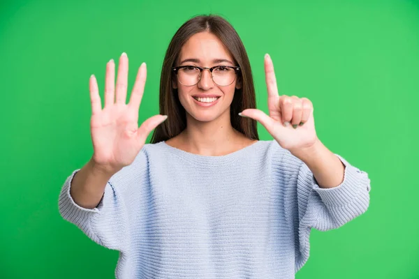 ヒスパニック系のかなり女性は笑顔と友好的に見える 前方に手で数字7または7番目を示し カウントダウン — ストック写真