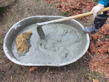 İnşaat işçileri havan topu ile karıştırılmış kum ve su harcı birlikte karıştırmak için kullanıyorlar. bir ev inşa etmek için alçıda kullanmak için
