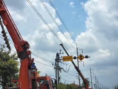 Tramvaydaki elektrikçi deneyimli uzmanlar yol boyunca elektrik hatları yönlendiriliyor. Çok fazla dikkat gereklidir. Toplumu kolaylaştırmak için kurulan elektrik kablolarında, Pathum Thani-Tayland, 2022-04-24