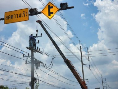 electrician on cable car Experienced experts Power lines are being routed along the roadside. A lot of caution is required. in the installation of electric cables to facilitate the community ,Pathum Thani-Thailand, 2022-04-24