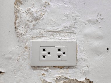 Suyla sızan beton duvardaki elektrik prizi duvardaki boyanın soyulmasına ve şişmesine neden oluyor. Bu da sızıntı akıntısının insanlar için tehlikeli olmasına neden oluyor..