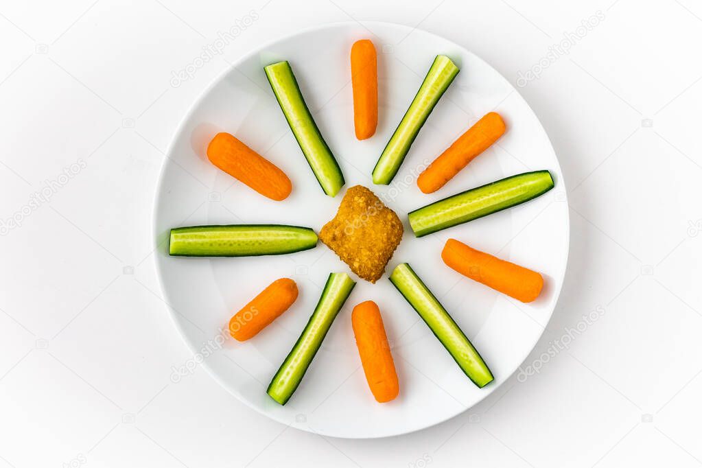 Chicken nugget cucumber slices and mini carrots arranged on white porcelain plate