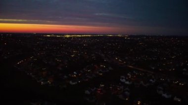 Drone panorama revealing golden sunset above neighborhoods of Lexington, Kentucky with night traffic going in all directions on the streets bellow