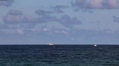 Denizcilik gemilerinin çeşitliliği arasında kanolar, su jetleri, okyanus yüzeyinden Fort Lauderdale Sahili 'ne yakın bir yerde, ufukta görünen büyük bir gemi ile geçen tekneler var.