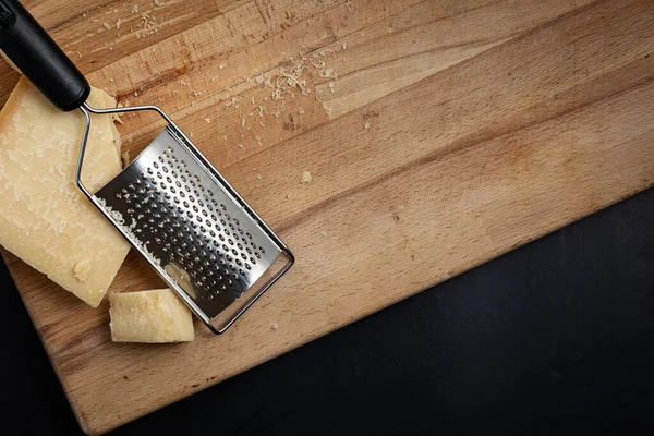 Parmesan peyniri rendelenmiş. Kesme tahtasının üzerinde çerçevenin açısına yerleştirilmiş rende var.