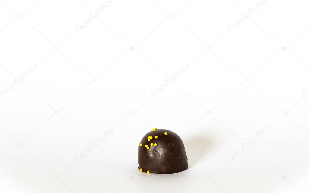 Gourmet dark chocolate candy with bright yellow sprinkles isolated on white background