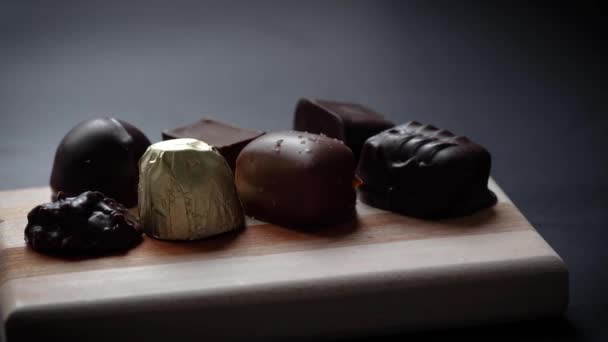 Schuiven Van Verschillende Gastronomische Chocolade Snoepjes Geplaatst Houten Plank Grijze — Stockvideo