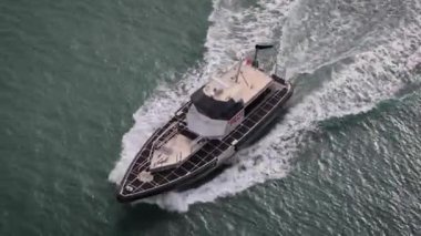 Bir geminin yanındaki pilot sürat teknesinin yörüngesini takip ediyorum.