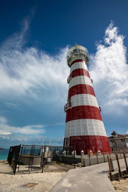 Tepeden tırnağa, Karayip denizindeki tropik adada bulunan kırmızı ve beyaz çizgili klişe deniz fenerinin manzarası