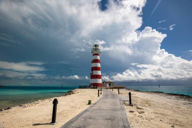 Etrafı kumla çevrili asfalt bir deniz feneri. 