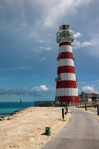 Etrafı kumla çevrili asfalt bir deniz feneri.