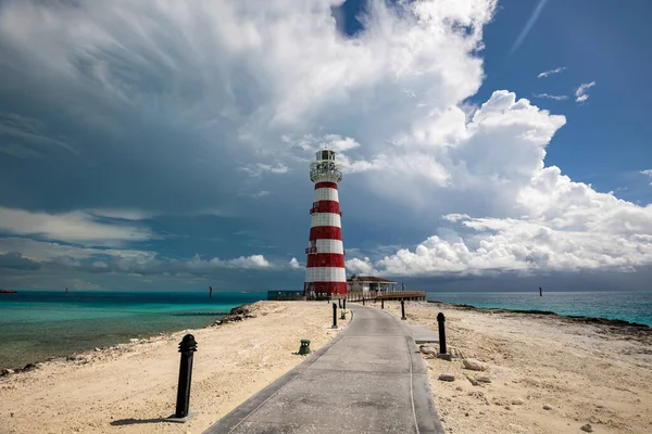 Etrafı kumla çevrili asfalt bir deniz feneri. 