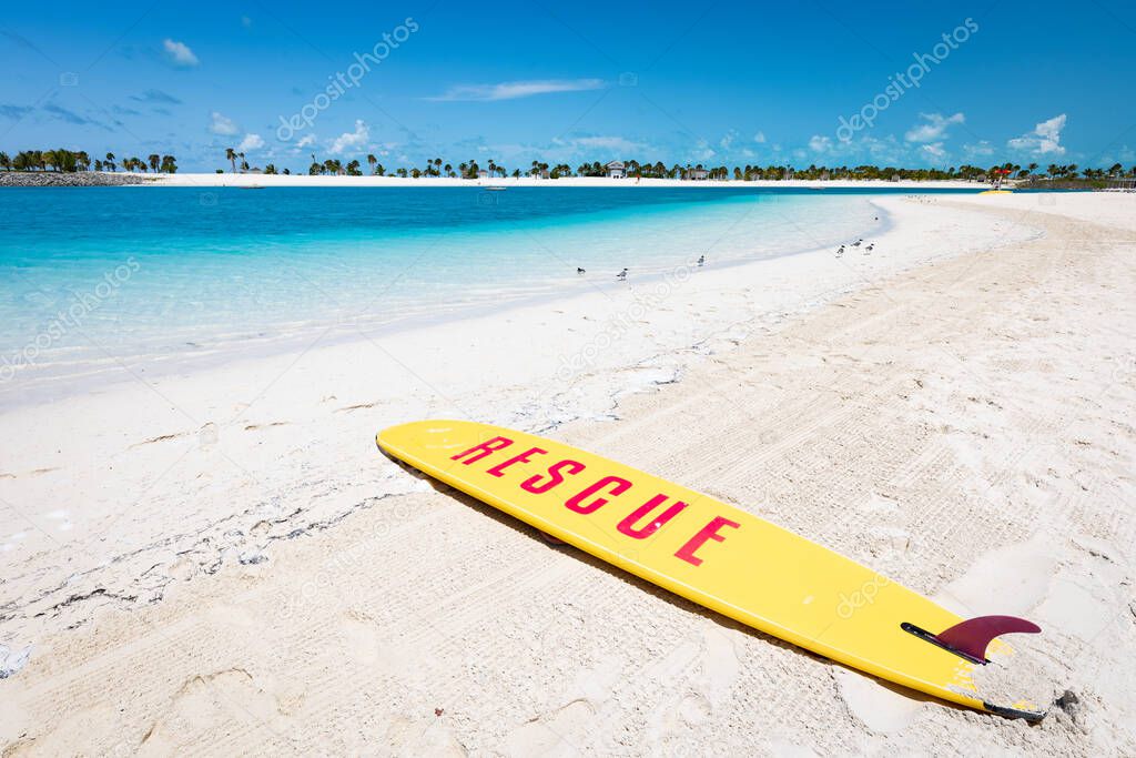 Rescue surf board on a bank of groomed tropical beach