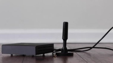 A cable running on the floor leading to an antenna and helium cryptocurrency mining device