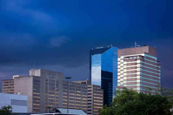 Lexington, Kentucky şehir merkezindeki yüksek finans ofislerinin arkasındaki kara bulutlar. Yüksek gökdelenlerin mavi lekeli camlarına güneş ışığı yansıyor.
