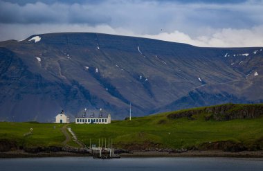 İzlanda 'da volkanik dağ sırasının eteklerindeki küçük ev su koyunun diğer kıyısından görüldü.