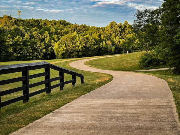 Curves of a path forward in Veteran\'s park in Lexington, Kentucky. Wooden fence as a rail in the left side of the image