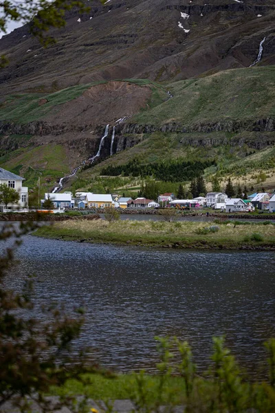 Houses in front of the waterfall on the slops of a mountains in the town of Seydisfjordur in Iceland