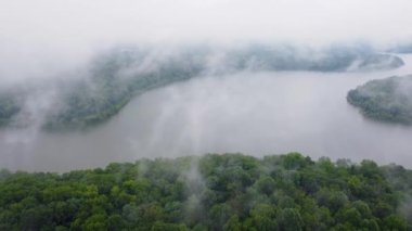 Approaching and flying through low clouds over forests around Taylorsville lake in Kentucky